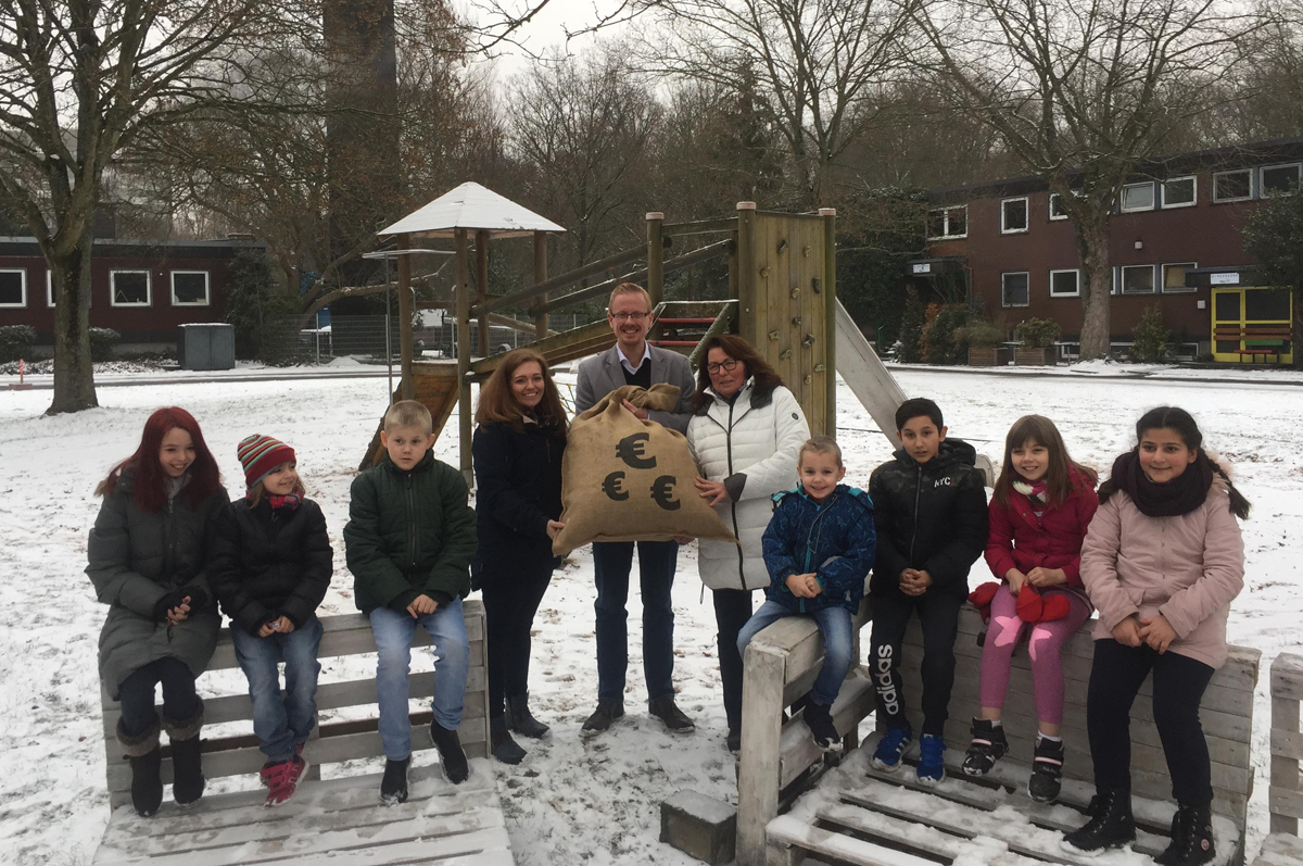 Restcent-Spendenübergabe im Kinderdorf Duisburg: Drei Erwachsene mit Jutesack und Kindergruppe auf verschneitem Spielplatz.