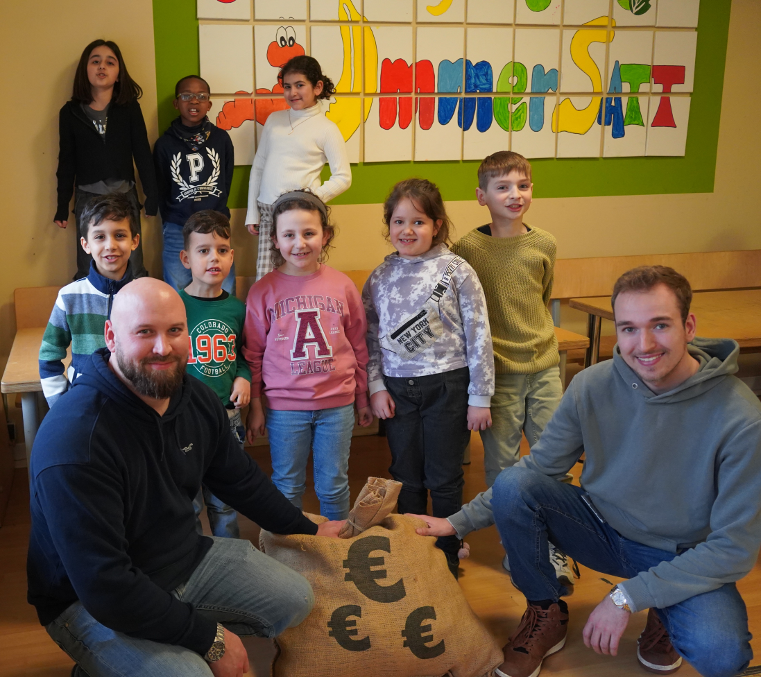 Azubi Philipp Palm übergibt den Restcentspendensack an Michael Zeltsch und Kinder vom Immersatt e. V.