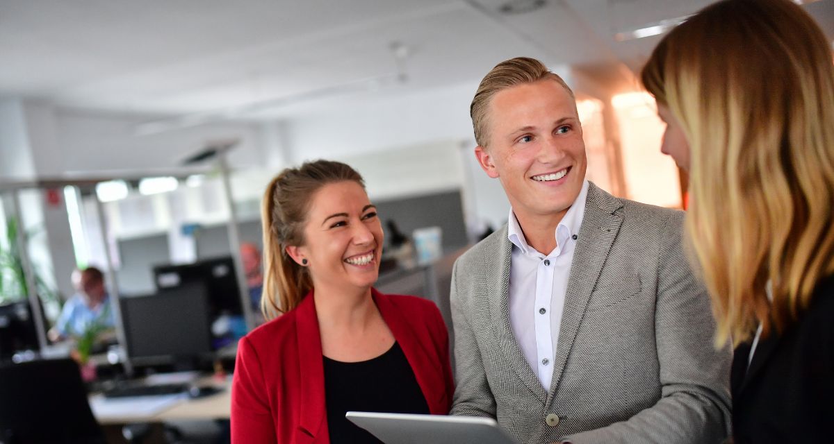 Drei junge Menschen im Gespräch in einem modernen Büro